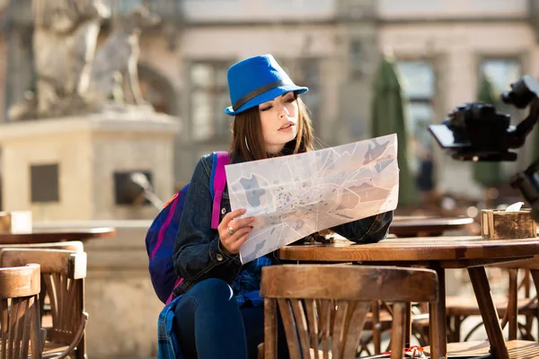 Giovane ragazza con un cappello blu che riposa sulla terrazza estiva nel centro storico, e guardando la mappa. Lviv, Ucraina — Foto Stock