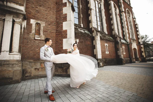 Menakjubkan tersenyum pasangan pernikahan. Cantik pengantin dan bergaya pengantin pria dekat gereja — Stok Foto