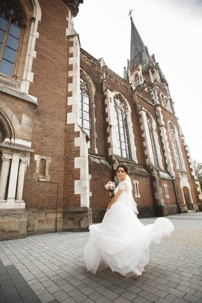 Die Braut auf einem Spaziergang nahe der Mauer der alten gotischen Kirche — Stockfoto