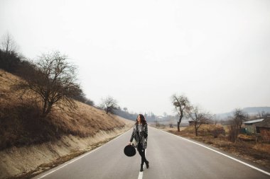 Güzel bir gri hırka ve yol boyunca siyah şapka sürmek mutlu kadın