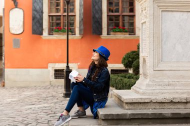 Genç bir turist, Lviv'deki kırmızı duvarın yakınında, eski avludaki merdivenlerde oturuyor. Ukrayna