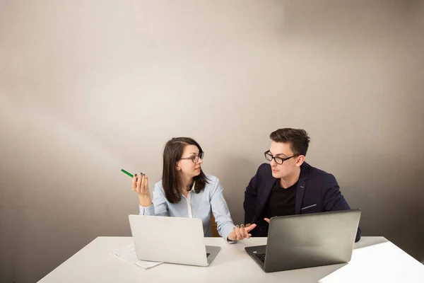 Молоді ділові партнери чоловічої та жіночої статі сидять за монітором комп'ютера і думають про щось — стокове фото