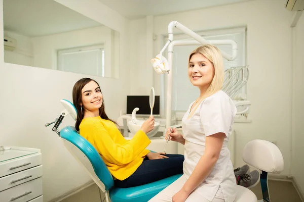 Giovane cliente donna felice guardando lo specchio con sorriso dentato allo studio dentistico vicino al medico — Foto Stock