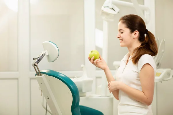 Dentista sonriendo y sosteniendo una manzana verde, cuidado dental y concepto de prevención — Foto de Stock