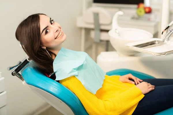 Ritratto di una donna dal sorriso dentato seduta sulla sedia dentale dello studio dentistico Foto Stock