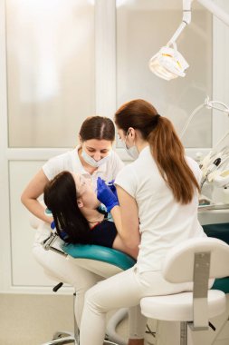 Doktor whit asistanı hastanın dişlerini tedavi ediyor, çürükleri engelliyor. Stomatoloji kavramı