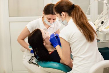 Doktor whit asistanı hastanın dişlerini tedavi ediyor, çürükleri engelliyor. Stomatoloji kavramı