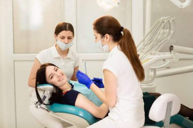 Doktor whit asistanı hastanın dişlerini tedavi ediyor, çürükleri engelliyor. Stomatoloji kavramı