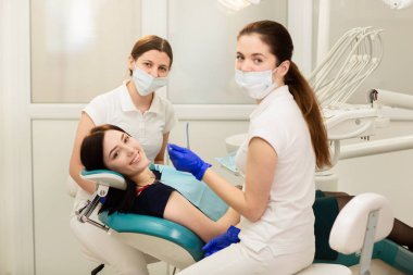 Doktor whit asistanı hastanın dişlerini tedavi ediyor, çürükleri engelliyor. Stomatoloji kavramı