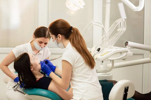 Medico assistente di latte che cura i denti del paziente, prevenendo la carie. Concetto di stomatologia — Foto Stock