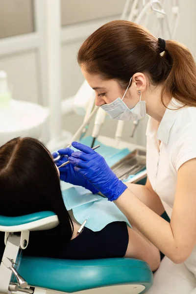 Closeup portrait of young woman patient, sitting in dentist chair. Doctor examines the teeth. Dental health prevention — Stock Photo, Image