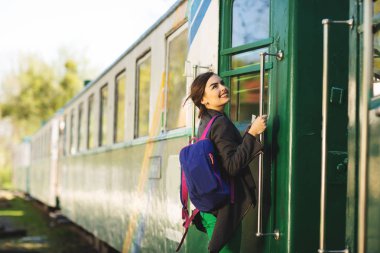 Sırt çantalı genç güzel bir kadın tren istasyonunda trenle seyahat etmeye gider. Seyahat ve yaşam tarzı kavramı