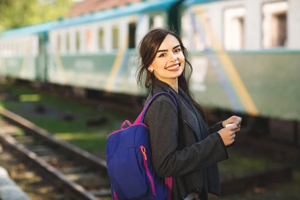 Wanita dengan ransel, dekat kereta api memeriksa tiketnya ke stasiun — Stok Foto