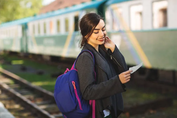 Donna con uno zaino, vicino al treno controlla il suo biglietto per la piattaforma della stazione — Foto Stock