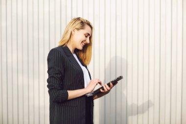 Açık hava kahve molası sırasında, ofis binasının yanında tablet bilgisayar kullanan genç bir iş kadını. İletişim konsepti