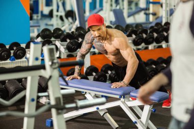 Spor salonunda antrenman yaparken yedek kulübesinde şınav çeken güçlü bir sporcu.