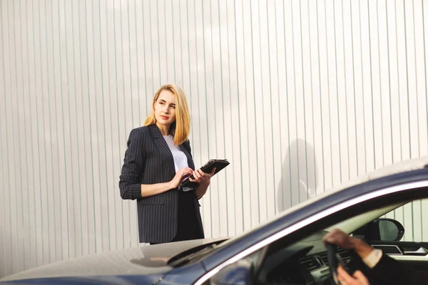 Dokumenty kontrolne przez pracownika kobiety, w pobliżu czarnego samochodu — Zdjęcie stockowe