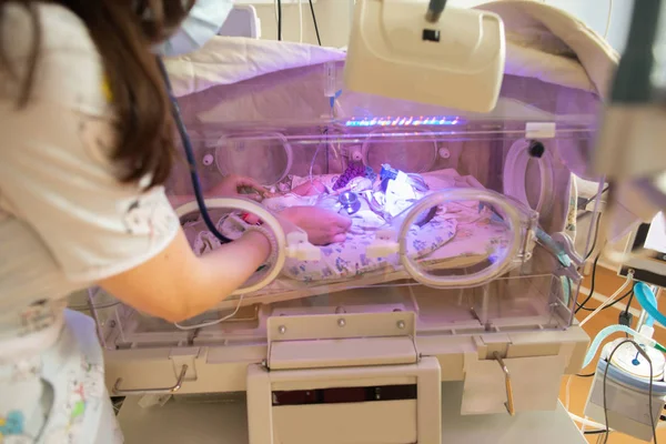 Vrouwelijke arts onderzoekt pasgeboren baby in incubator. close-up vrouwelijke handen met een stethoscoop — Stockfoto