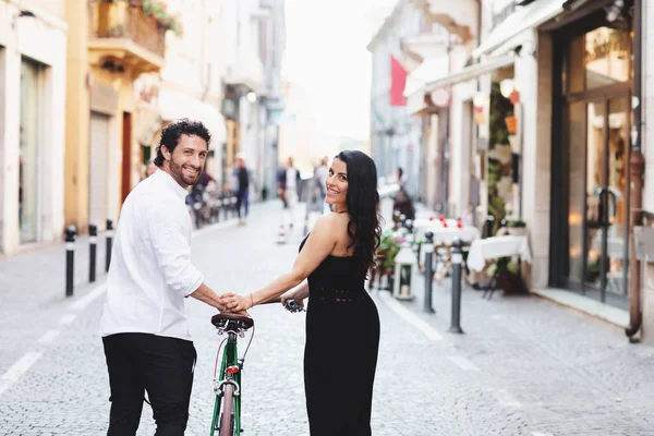 Vackert klädd man och kvinna går i den gamla staden med en cykel. Kärlekshistoria i Rimini, Italien. Back View — Stockfoto