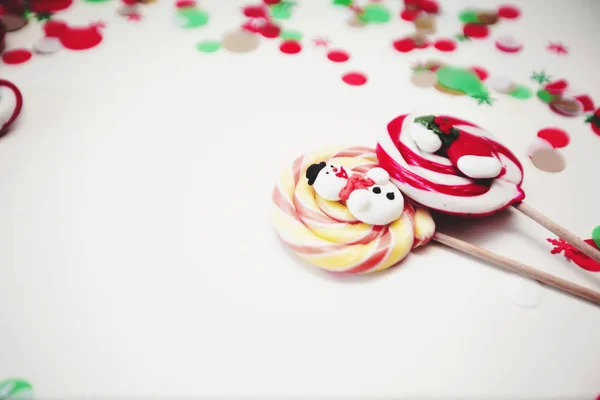 Nahaufnahme von weihnachtlich gestreiften und farbigen Lutschern. Bonbons auf weißem Hintergrund mit Konfetti — Stockfoto
