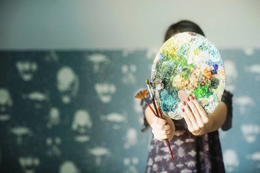 Bir kadın önünde yağlı boya lar ve fırçalar bir palet tutar. Sanat kavramı