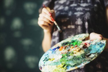 Yağlı boyalarla fırça ve palet tutan kadın elleri. Yakından kapatın. Sanat kavramı