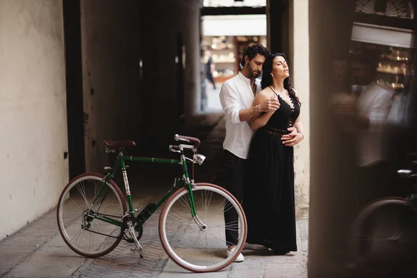 Photo session of love couple. A man and a woman are walking in the old city with a green retro bike