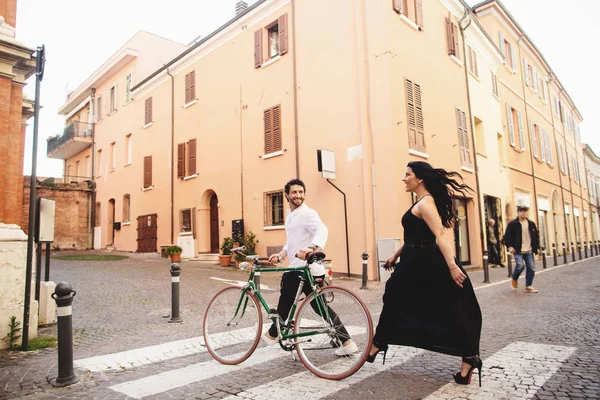 Homem e mulher lindamente vestidos estão andando na cidade velha com uma bicicleta. História de amor em Rimini, Italia — Fotografia de Stock
