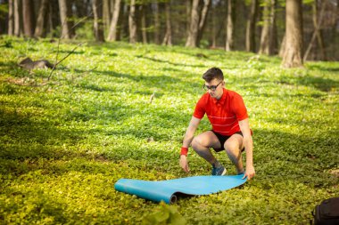 Adam egzersizleri ve rahatlama için yeşil çim bir parkta mavi bir yoga minderi yayılır. Sağlıklı yaşam tarzı