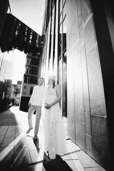 El marido sostiene a su esposa embarazada de la mano. Una pareja paseando por la ciudad. Alemania, Leipzig. Blanco y negro — Foto de Stock