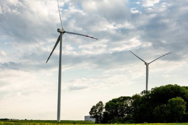 Sarı çiçeklerile parlak yeşil bir alanda Modern yel değirmeni. Ve yel değirmeni üzerinde beyaz bulutlar ile mavi gökyüzü