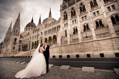 Gelin ve damat eski kasaba sokakta sarılmak. Düğün çift Budapeşte 'de Parlamento Evi yakınında yürüyor.