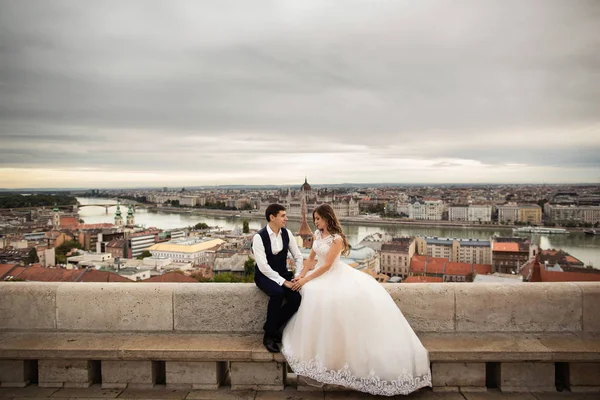 Jonge mooie stijlvolle paar jonggehuwden zittend door de Fisherman's bastion in Boedapest, Hongarije — Stockfoto