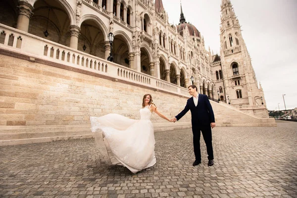 Bruid en bruidegom knuffelen in de oude stad straat. Bruiloft paar wandelingen in Boedapest in de buurt Parliament House. — Stockfoto