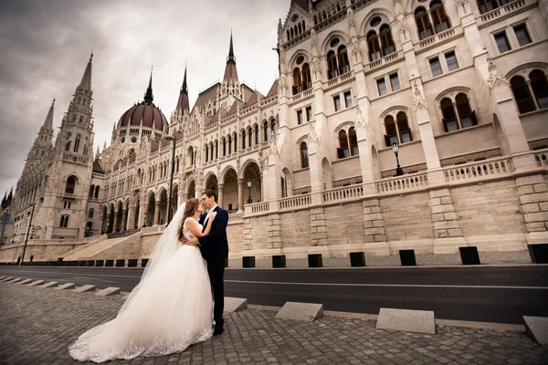 Bride and groom hugging in the old town street. Wedding couple walks in Budapest near Parliament House. Stock Photo