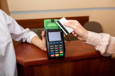 Kadın doktor hizmetleri için kredi kartı ve terminal ile öder. Terminal ve kredi kartı tutan kadın ellerinin kapatılması