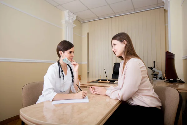 Dokter perempuan duduk di meja di kantor dan menulis resep untuk pasien . — Stok Foto