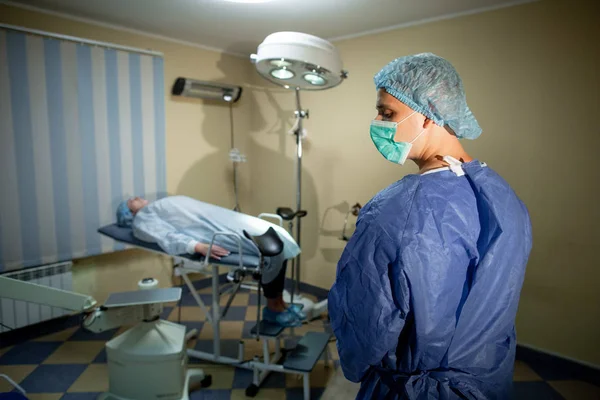 Dokter bedah berdiri dengan punggung ke kamera. Sebelum dia di meja operasi terbaring seorang pasien. Persiapan untuk operasi — Stok Foto