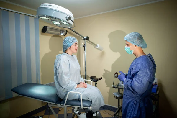 Dokter bedah berdiri dengan punggung ke kamera. Sebelum dia di meja operasi duduk seorang pasien. Persiapan untuk operasi — Stok Foto