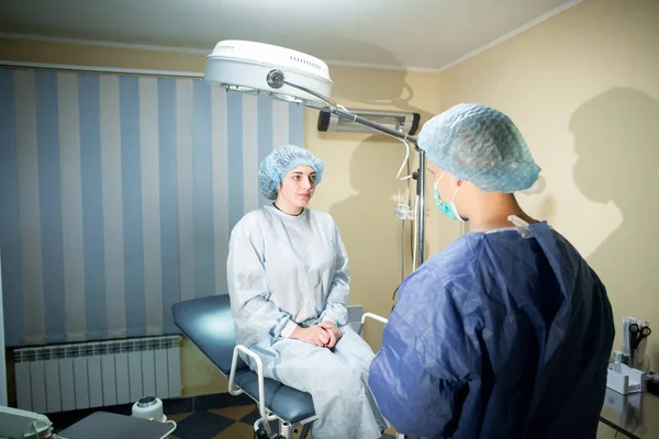 The surgeon stands with his back to the camera. Before him on the operating table sits a patient. Preparation for surgery