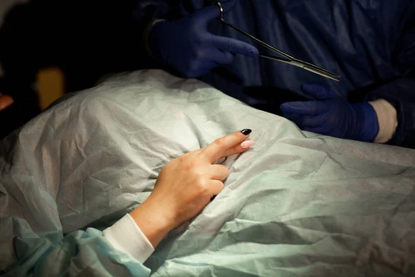 Chirurg en patiënt in de operatiekamer. Vrouw kruiste haar vingers voor geluk voor de operatie. Chirurg houdt een schaar in zijn hand. Sluiten. — Stockfoto