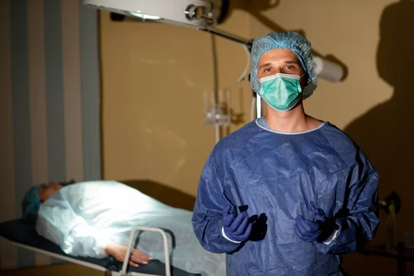 Egy nyugodt sebész fényképe egy beteggel a háttérben. Műtétre való felkészülés Stock Kép