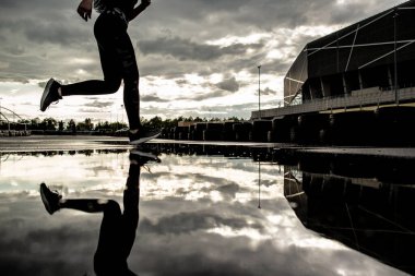 Spor geçmişi. Hareket halindeki bir koşucunun güçlü atletik bacakları. Yağmurdan sonra dışarıda kardiyo çalışması yapan bir kadın..