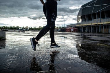 Spor geçmişi. Hareket halindeki bir koşucunun güçlü atletik bacakları. Yağmurdan sonra dışarıda kardiyo çalışması yapan bir kadın..