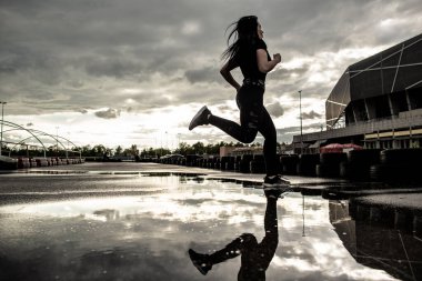 Spor geçmişi. Hareket halindeki bir koşucunun güçlü atletik bacakları. Yağmurdan sonra dışarıda kardiyo çalışması yapan bir kadın.