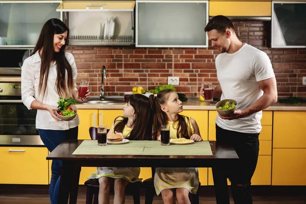 Gesunde Ernährung gegen schlechte Gewohnheiten. Eltern bieten ihren Töchtern statt Burger und Limo einen Salat mit Saft an. Kleine Mädchen sind nicht glücklich. Junk Food-Konzept — Stockfoto