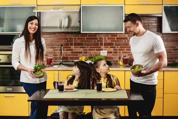 Makan sehat vs kebiasaan buruk. Orang tua menawarkan putri mereka salad dengan jus bukan burger dan soda. Gadis kecil tidak bahagia. Konsep makanan sampah — Stok Foto