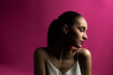 Pembe arka planda genç bir kadının portresi. Kadınların başı yana döner, gözleri kapanır.