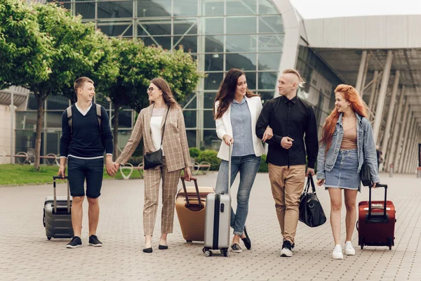 Felizes jovens positivos com bagagem ao ar livre perto do aeroporto. Amigos que retornam de uma viagem — Fotografia de Stock