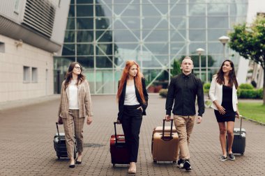 Ön manzara, mutlu genç insanlar, üç kadın ve havaalanı yakınlarında bagajlı bir adam. Seyahatten dönen arkadaşlar. Seyahat ve tatil kavramı